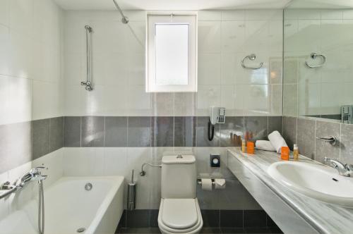 a bathroom with a sink and a toilet and a tub at Kipriotis Village Resort in Kos Town