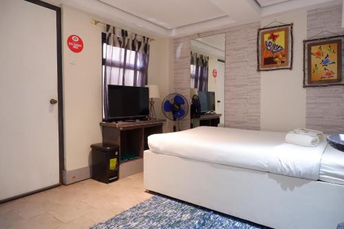 a hotel room with a bed and a television at Sunset View Ridge Residences in Baguio