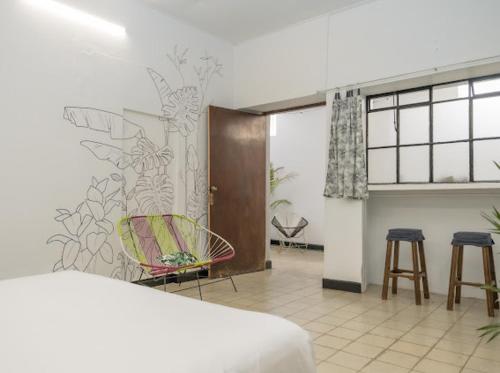 una habitación con 2 sillas y una pared con un mural en The cool house Habitación 2, en Ciudad Guzmán