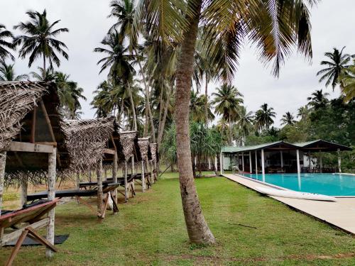 un resort con piscina e palme di Helios Beach Resort a Tangalle