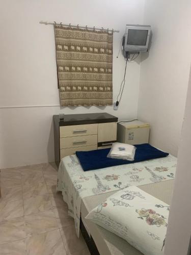 a small room with two beds and a tv at Pousada Recanto do Mar in Saquarema