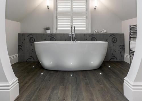 a white bath tub in a bathroom with wooden floors at Brocco On The Park Boutique Hotel in Sheffield