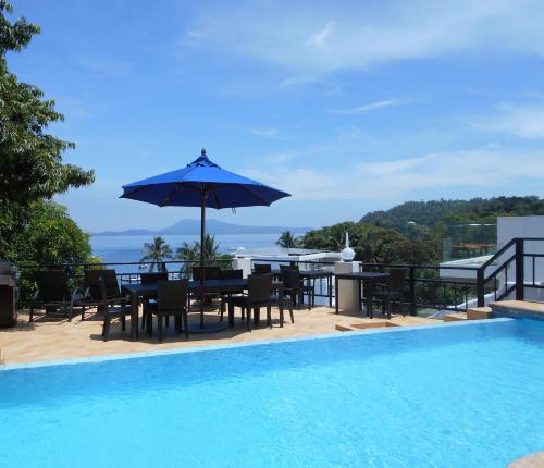 a patio with a table and umbrella next to a swimming pool at Out of the Blue Resort in Puerto Galera