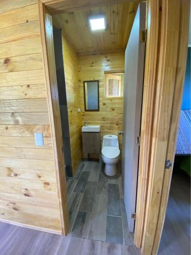 La salle de bains en bois est pourvue de toilettes et d'un lavabo. dans l'établissement Cabañas del Llano, à Puyehue