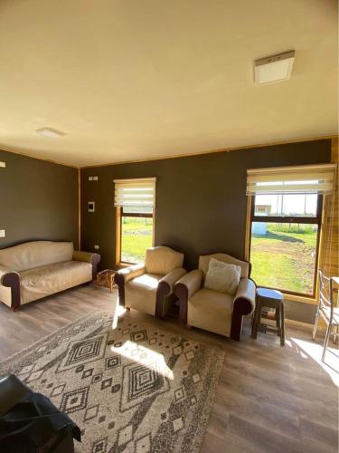 ein Wohnzimmer mit 2 Betten, einem Sofa und einem Teppich in der Unterkunft Cabañas del Llano in Puyehue
