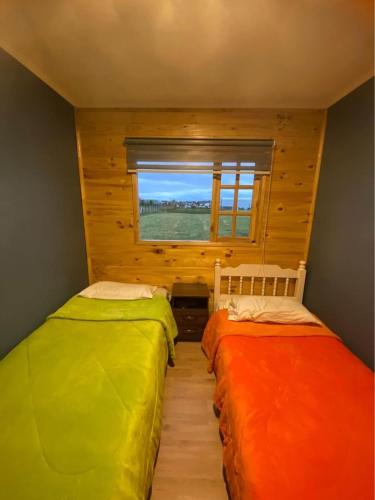 2 Betten in einem Zimmer mit Fenster in der Unterkunft Cabañas del Llano in Puyehue