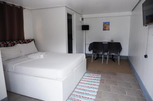 a white bed in a room with a table and chairs at Sunset View Ridge Residences in Baguio