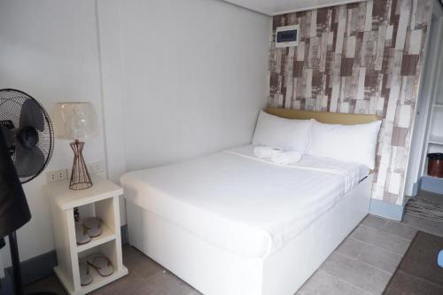 a small bedroom with a white bed and a fan at Sunset View Ridge Residences in Baguio