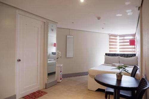 a bedroom with a bed and a table and a room with a bed at Sunset View Ridge Residences in Baguio