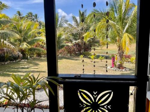 a window with a view of a park with palm trees at Are Mii a stylish one room container home in Rarotonga