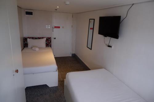 a small room with two beds and a flat screen tv at Sunset View Ridge Residences in Baguio