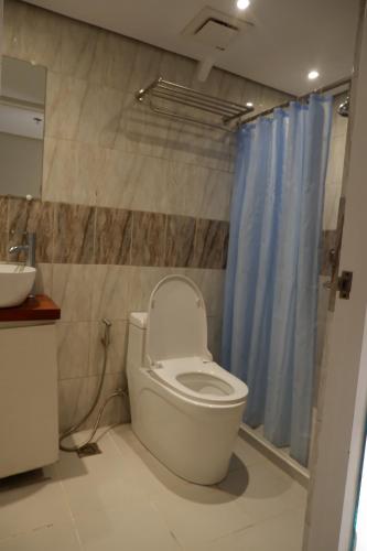 a bathroom with a toilet and a blue shower curtain at Sunset View Ridge Residences in Baguio