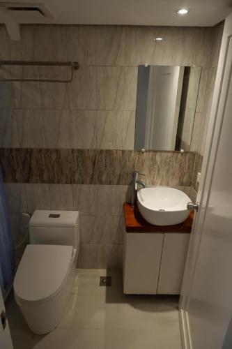 a bathroom with a toilet and a sink and a mirror at Sunset View Ridge Residences in Baguio