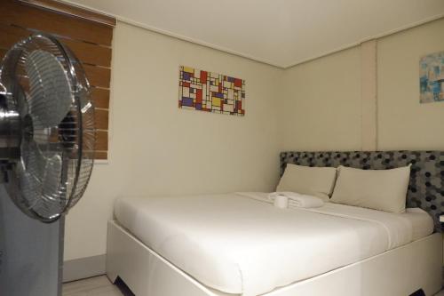 a bedroom with a white bed and a fan at Sunset View Ridge Residences in Baguio