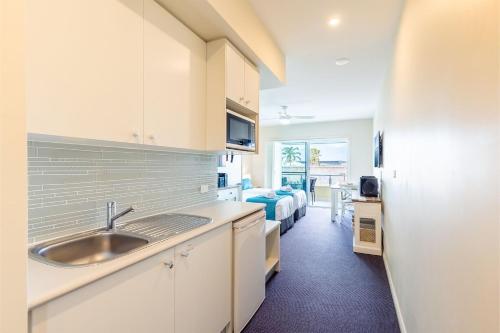 a kitchen with a sink and a room with a bed at Pacific Blue 278-265 Sandy Pt Rd- Dual Key Access, Wifi, Linen and Air Conditioning in Salamander Bay