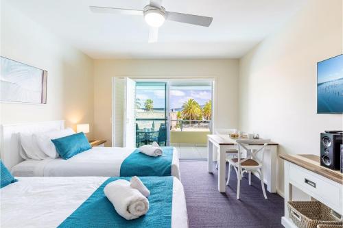 1 dormitorio con 2 camas, escritorio y mesa en Pacific Blue 278-265 Sandy Pt Rd- Dual Key Access, Wifi, Linen and Air Conditioning, en Salamander Bay