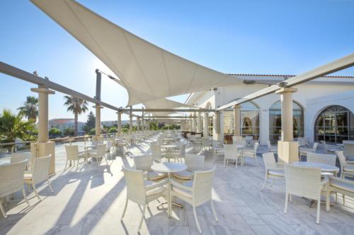 a row of white chairs and tables on a patio at Kipriotis Village Resort in Kos Town