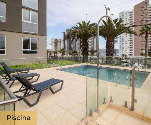 a swimming pool with two lounge chairs next to a building at La herradura departamento nuevo a pasos de la playa 2 dorm 1 baño in Coquimbo