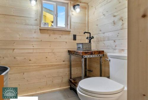 La salle de bains en bois est pourvue de toilettes et d'une fenêtre. dans l'établissement Blue Tiny Home@Cloverdale Cabins, à Hinckley