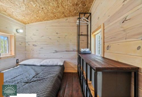 1 dormitorio con 1 cama y pared de madera en Blue Tiny Home@Cloverdale Cabins, en Hinckley