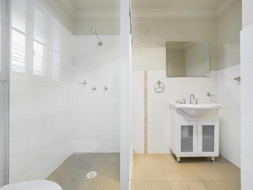 a white bathroom with a sink and a shower at 3A Kunama in Berridale