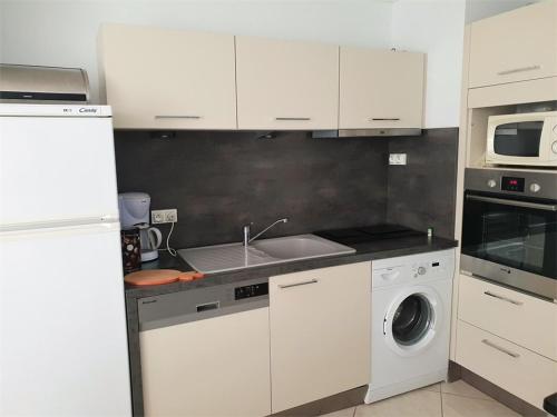 une cuisine avec des armoires blanches, un évier et un lave-vaisselle dans l'établissement T2 climatisé 4 pers avec loggia à 300m de la plage, Argelès-sur-Mer - FR-1-388-107, à Argelès-sur-Mer