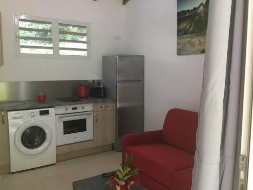 uma cozinha com uma máquina de lavar roupa e uma cadeira vermelha em Les Lucioles 1 Beau T2 en forêt tropicale avec accès piscine em Saint-Joseph