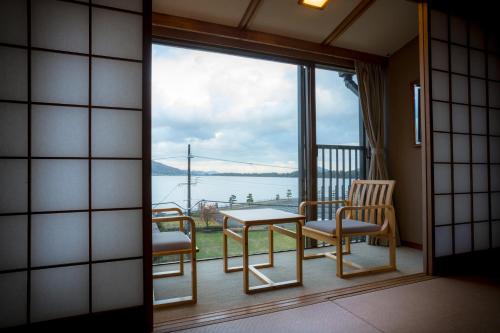 a room with a balcony with a view of the water at Hotel Kitanoya in Miyazu