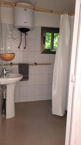 La salle de bains blanche est pourvue d'un lavabo et d'une fenêtre. dans l'établissement KASA BOUBAK, à Kafountine