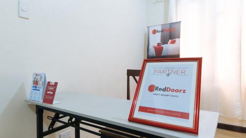 a table with a red door sign on it at RedDoorz @ Classique Pan Oriental Hotel and Resort Batangas in Batangas City