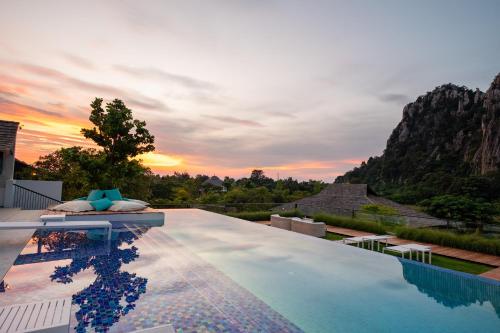 a swimming pool with a sunset in the background at The Soul Resort in Sara Buri