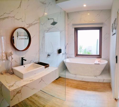 ein Badezimmer mit einem Waschbecken, einer Badewanne und einem Spiegel in der Unterkunft San Villa Syariah in Banjarbaru