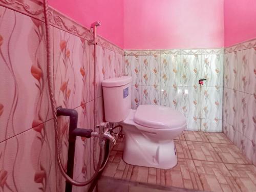 a bathroom with a toilet and a pink wall at Papilo House near Stasiun Nganjuk Mitra RedDoorz in Nganjuk