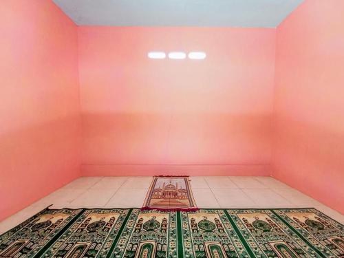 Una habitación rosa con una alfombra en el suelo. en Papilo House near Stasiun Nganjuk Mitra RedDoorz, en Nganjuk