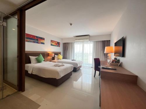 um quarto de hotel com duas camas e uma secretária e uma televisão em Riche Hua Hin Hotel - SHA Plus em Hua Hin