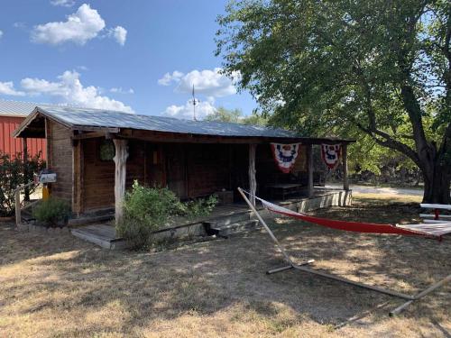 a small house with a hammock in front of it at Country Accents - Lee Cabin in Pipe Creek