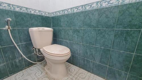 a bathroom with a toilet and a green tiled wall at Villa Pakis Residence Banyuwangi in Banyuwangi