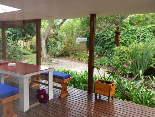 a patio with a table and chairs on a wooden deck at Tortuga - Peaceful Holiday Home with Loadshedding Backup in Sedgefield
