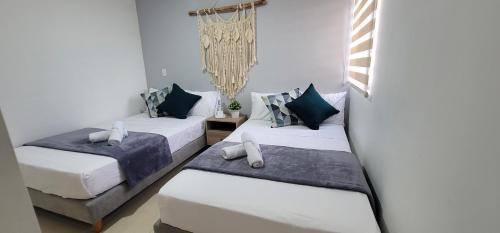 2 camas en una habitación con paredes blancas en APARTAMENTO en el QUINDIO, en La Tebaida
