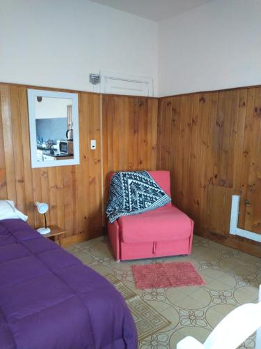 1 dormitorio con cama morada y silla rosa en Cómodo monoambiente a 5 minutos del centro! en San Carlos de Bariloche