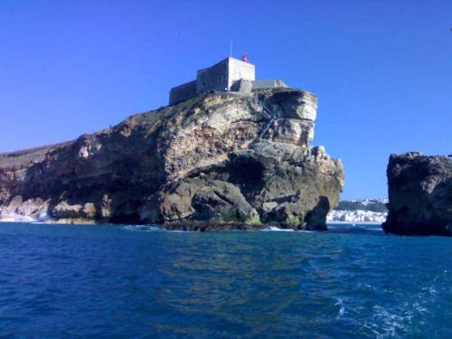 a lighthouse on top of an island in the water at Residencia Salva-Vidas in Nazaré