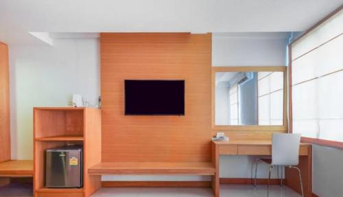 une pièce avec un bureau et une télévision sur un mur dans l'établissement The Little Nest Phuket, à Phuket