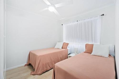 2 letti in una camera con pareti bianche e finestra di Alfred Street - Hosted by Burleigh Letting a Gold Coast