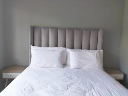 Cama blanca con sábanas y almohadas blancas en Vic's place - With backup power, en Sandton