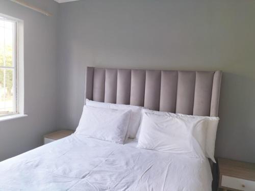 a bed with white sheets and pillows in a bedroom at Vic's place - With backup power in Sandton