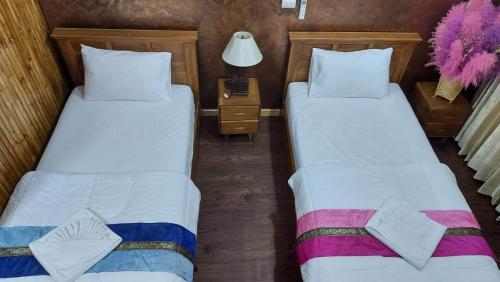 two twin beds in a room with a lamp at กอบสุข รีสอร์ท2 k12 in Ban Ton Liang