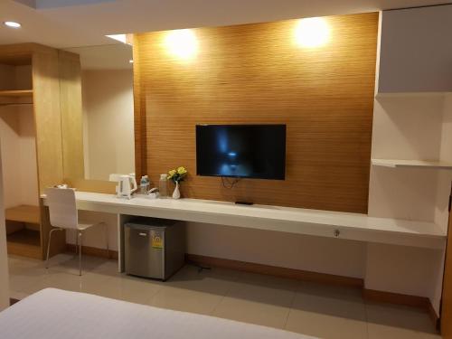 a hotel room with a desk with a tv on a wall at The Little Nest Phuket in Phuket