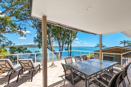 a patio with a table and chairs and the ocean at Waterfront Apartment - Soldiers Point in Soldiers Point