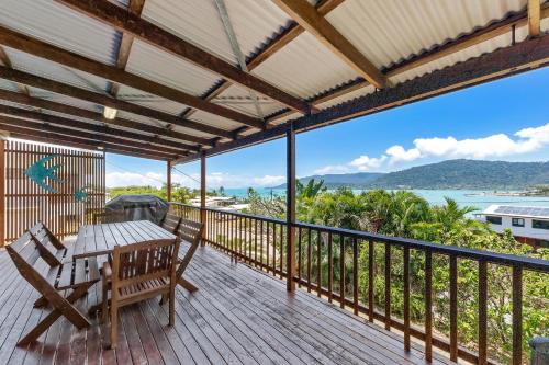 a deck with a table and chairs and a view of the ocean at Airlie Getaway - Airlie Beach in Airlie Beach