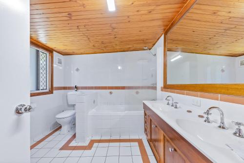 a bathroom with a tub and a toilet and a sink at Airlie Getaway - Airlie Beach in Airlie Beach